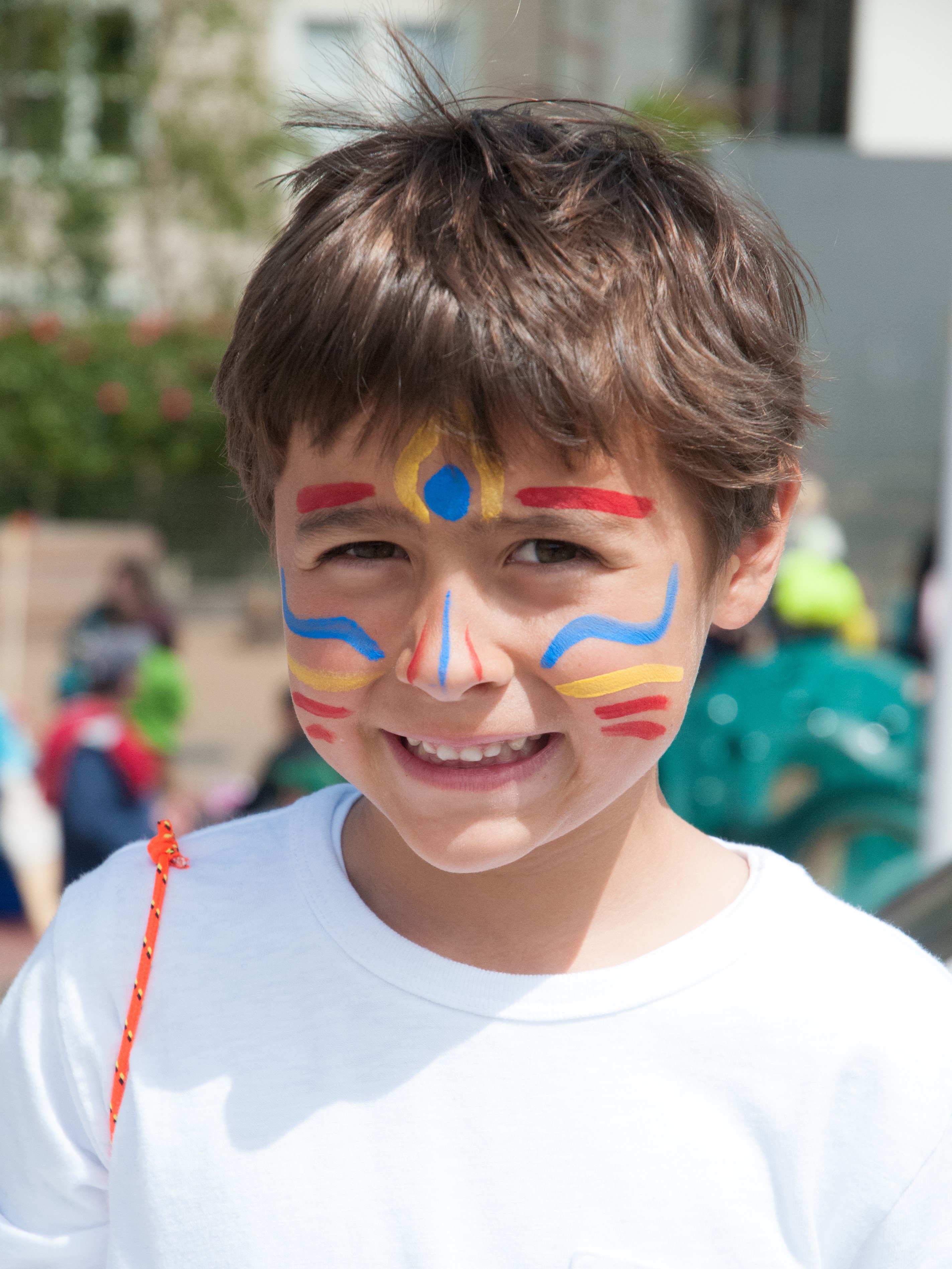 Child with face paint smiles at an outdoor school festival