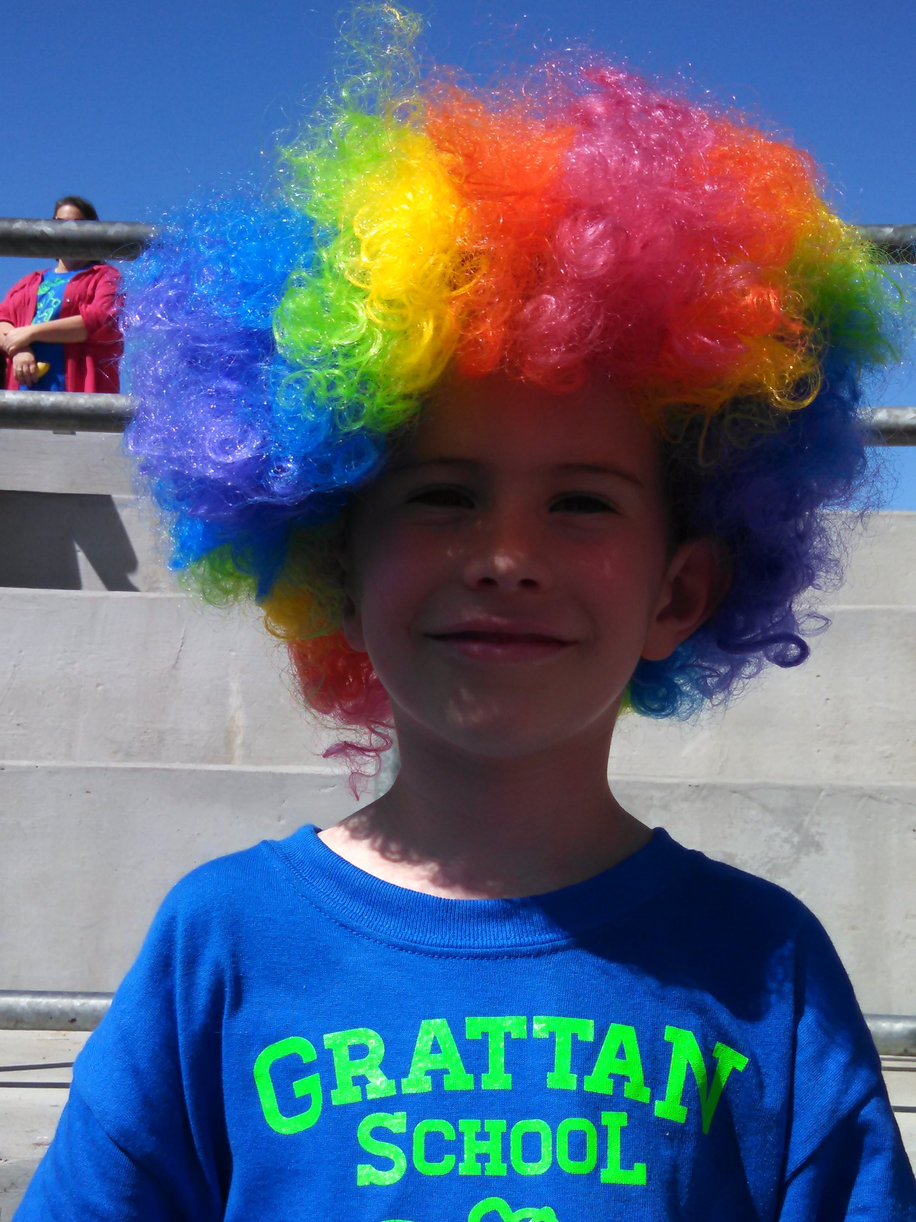 Child wearing rainbow wig at an outdoor school fitness event
