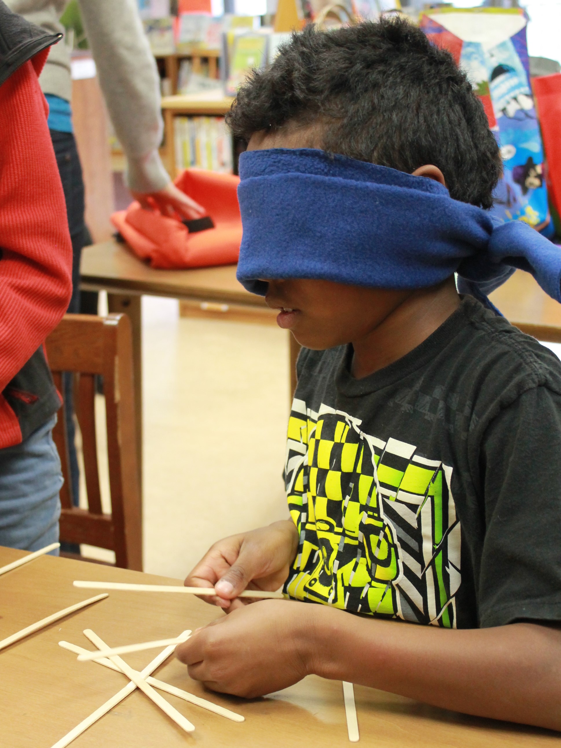 Boy with a blindfold tries to build a structure at a school inclusion awareness event
