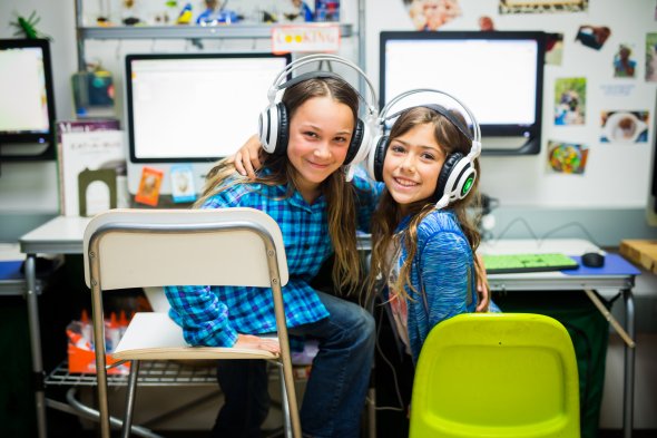 Two girls with headphones in front of computers