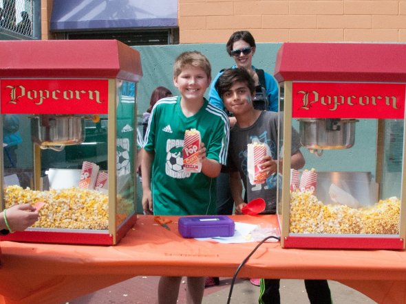 Two boys serving popcorn at an outdoor school festival