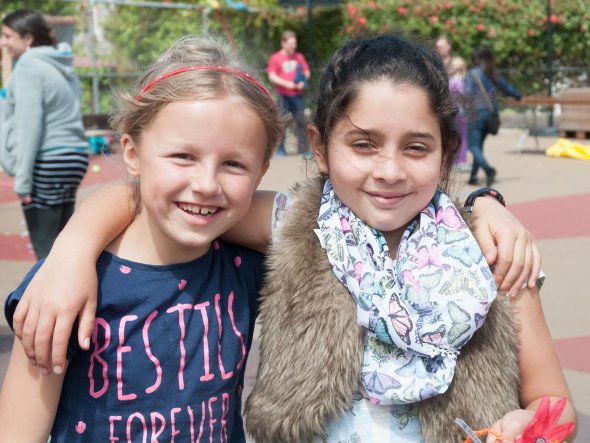 Two girls stand arm in arm at an outdoor school festival
