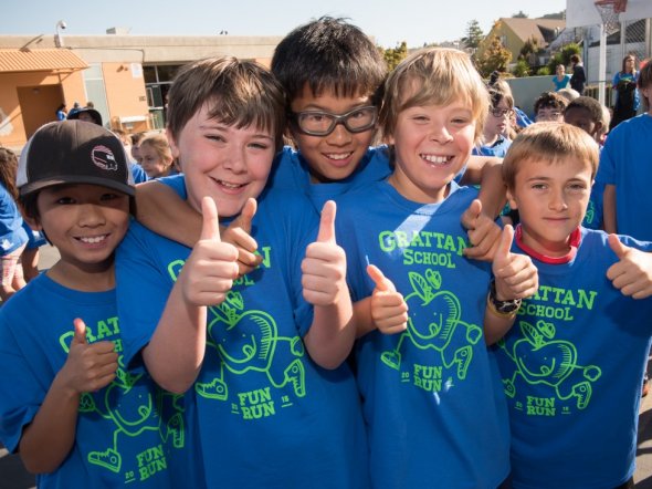 Five boys giving their thumbs up at an outdoor school fitness event