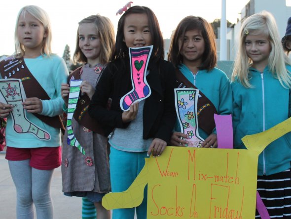 Five girls hold up handmade sock drawings to announce a school anti-bullying event