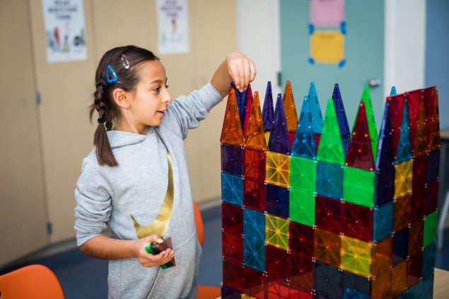 Girl building structure with magnetic tiles