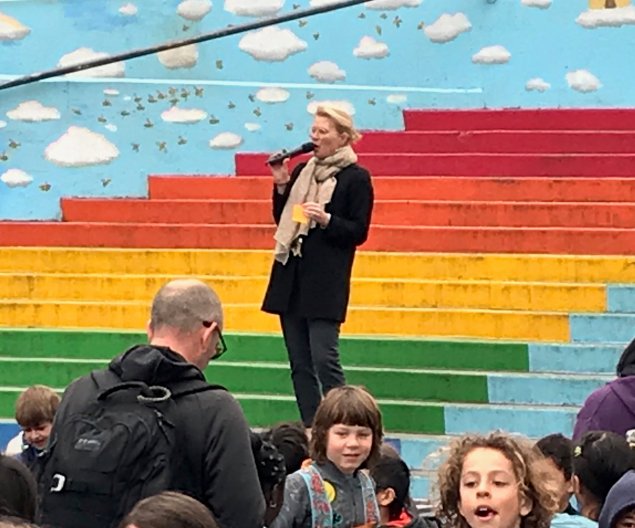 Woman standing on rainbow painted steps talking to group