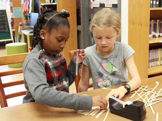 Two girls work together to build a structure at a school inclusion awareness event